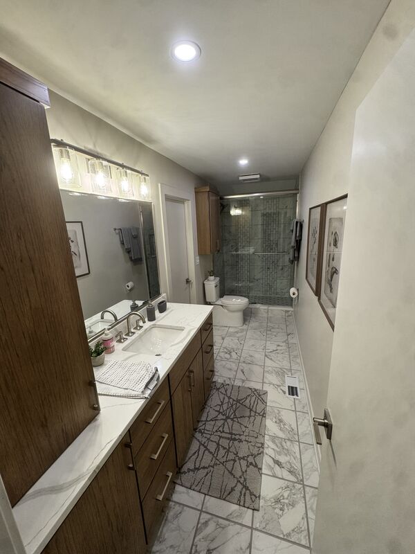 Bathroom with marble-look tile floor, glass shower and dark vanity