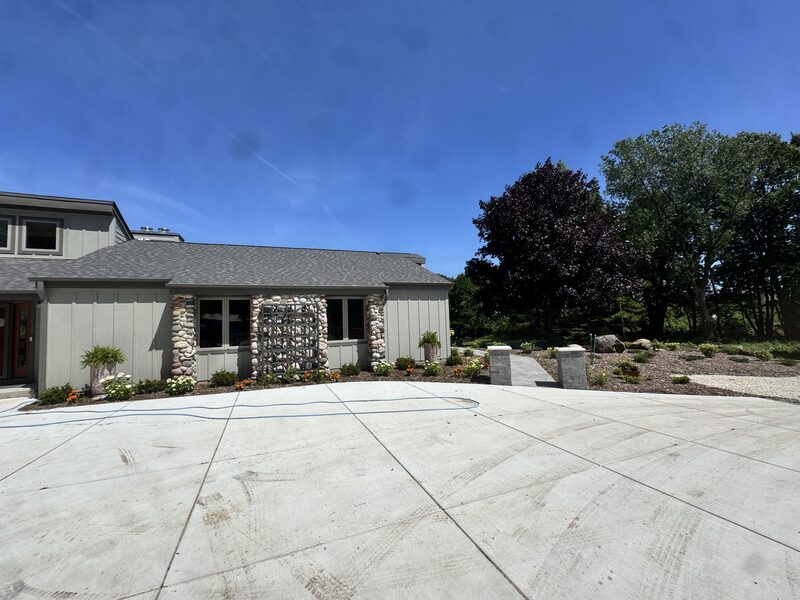 Custom home exterior with river-rock stone accents and a decorative stone-filled privacy screen between the windows