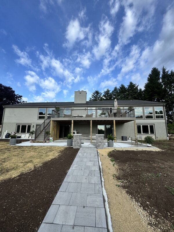 Two-story walkout custom home with a full-width elevated deck and paver walkway