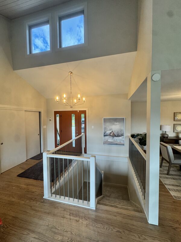Vaulted foyer with staircase, chandelier and front entry