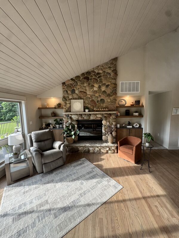 Great room with a fieldstone fireplace and vaulted shiplap ceiling