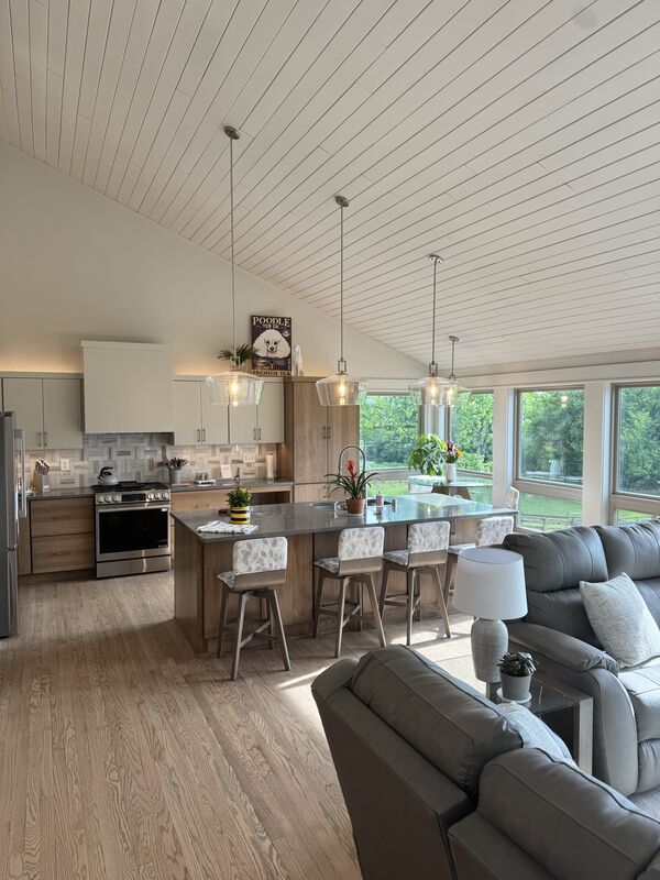 Open-concept kitchen and living room under a vaulted shiplap ceiling