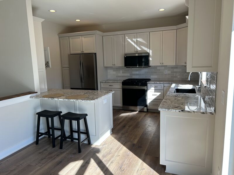 Bright kitchen with white cabinets, granite island and stainless appliances