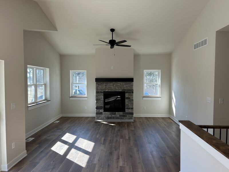 Bright living room with stone fireplace, hardwood floors and large windows
