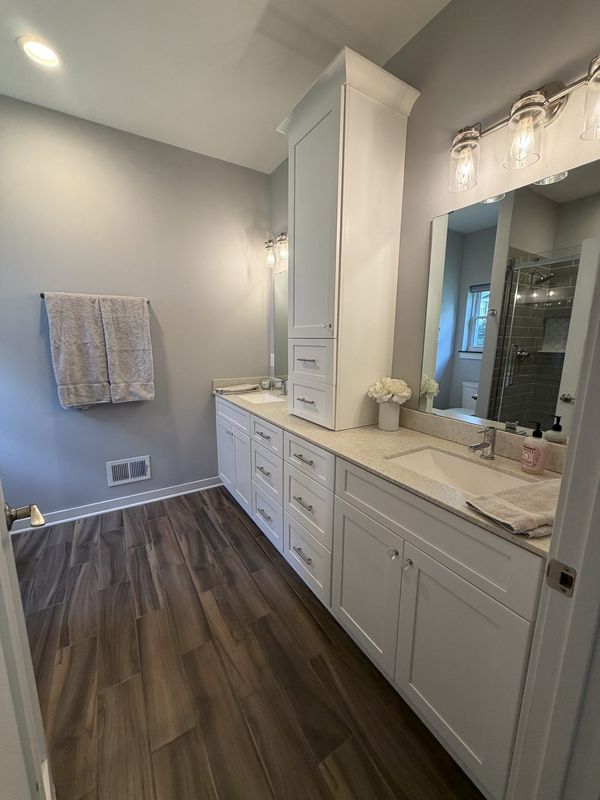 Full bath with a double vanity, framed mirror and custom cabinetry