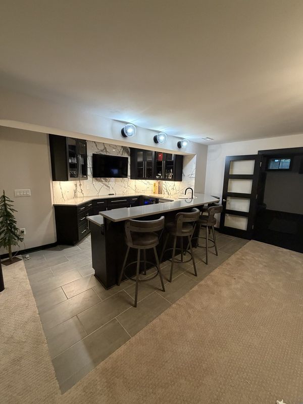 Custom kitchen with wet bar, dark cabinetry and bar seating