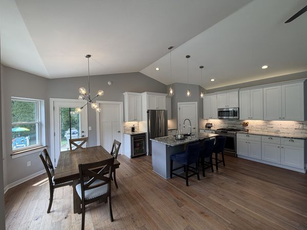 Custom kitchen and dining area with quartz island, pendant lighting and stainless appliances
