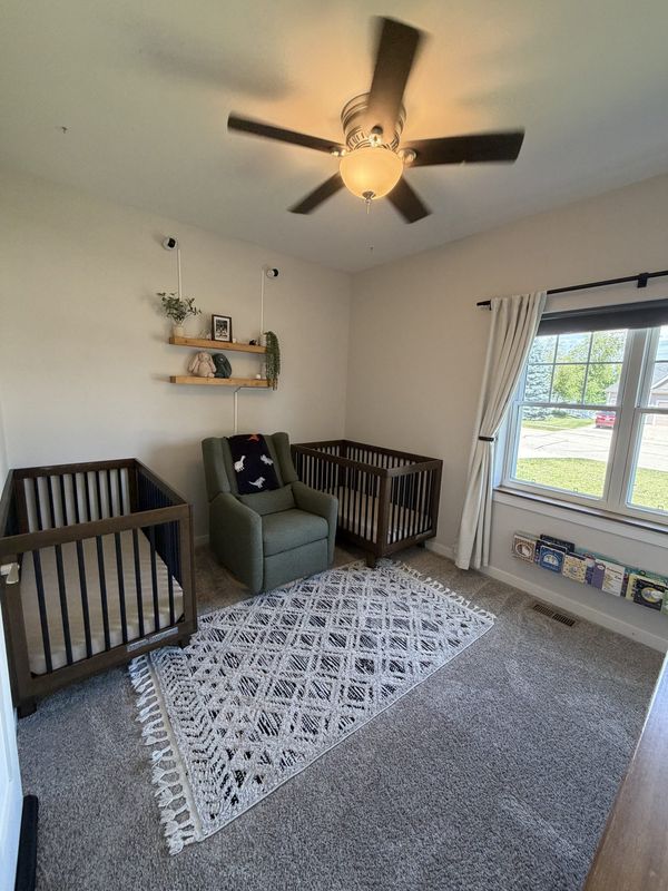 Vaulted, sunlit bedroom styled as a nursery with crib and shelving