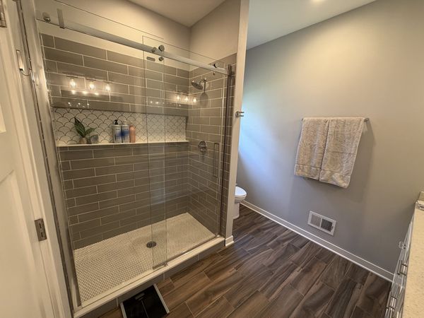Tiled walk-in shower with glass enclosure and built-in niche