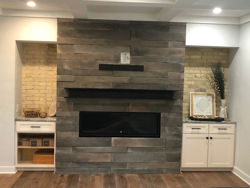 Modern linear fireplace with gray plank surround and built-in cabinets