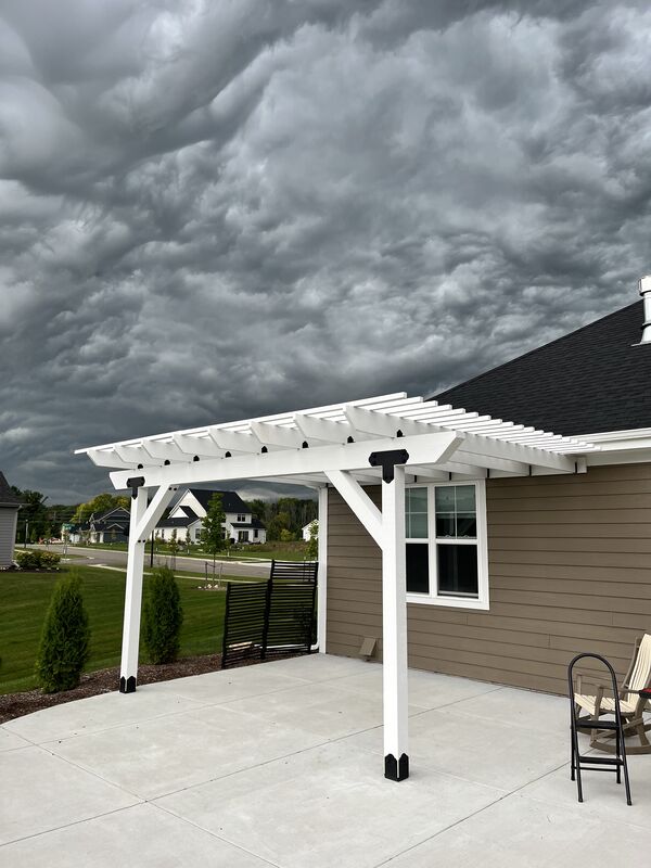 Custom white pergola over a concrete patio at the side of a home