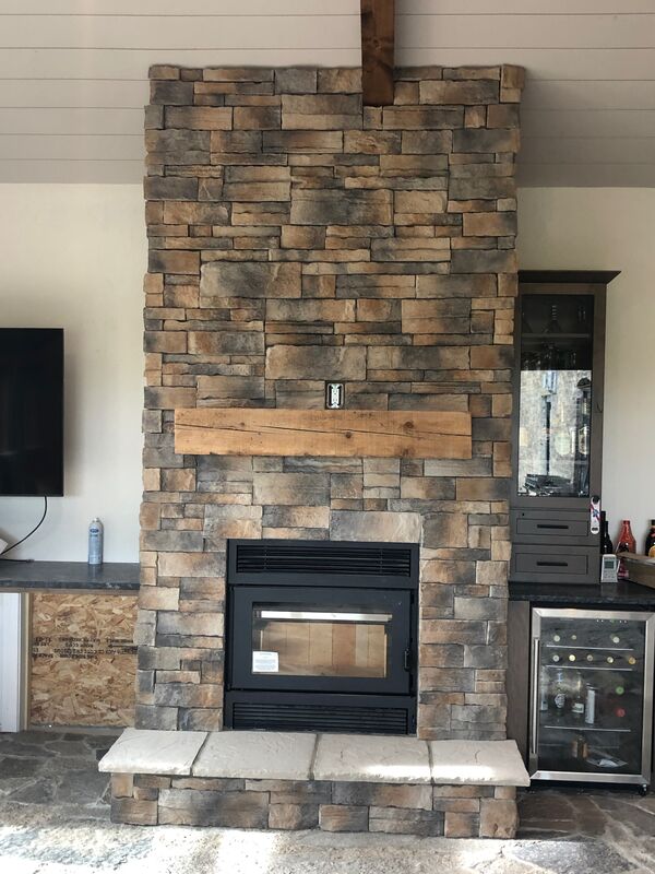 Floor-to-ceiling stacked-stone fireplace with reclaimed wood mantel